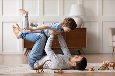 Sevinçten havalara uçmuş baba, sevimli oğlunla aktif oyun oynuyor.