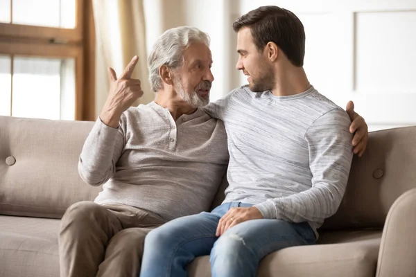 Happy older father and son having pleasant conversation at home
