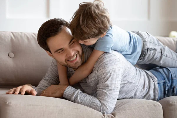 Крупним планом щасливий батько і син обіймаються, лежачи на дивані — стокове фото