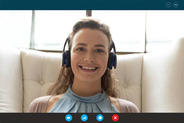 Bonita jovem sorrindo mulher em fones de ouvido segurando chamada de vídeo. — Fotografia de Stock