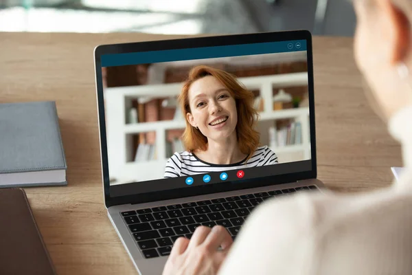 Souriante jolie femme aux cheveux roux tenant un appel vidéo avec un collègue. — Photo