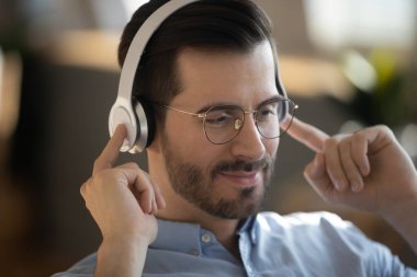 Kablosuz kulaklık takan adam internetteki ses kursunu dinliyor.
