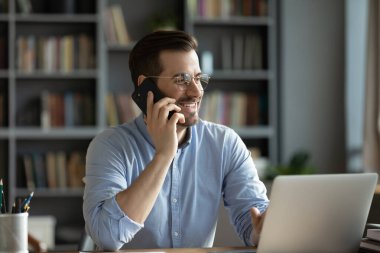 İş adamı iş yerinde elinde akıllı bir telefonla müşteriyle konuşuyor.