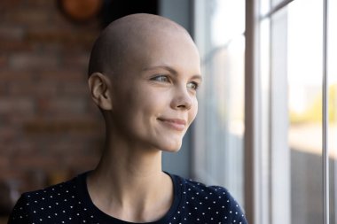 Onkolojik hastalığı olan umut dolu bin yıllık kadın büyük pencerenin yanında rüya görüyor.