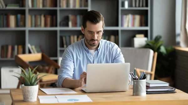 Focused businessman sit at workplace desk working on laptop