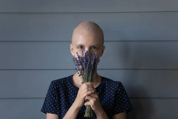 Young hairless woman hiding face in lavender bunch enjoying aroma — Stock Photo, Image
