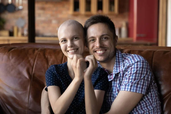 Loving husband hugging wife cancer patient on sofa at home — Stock Photo, Image