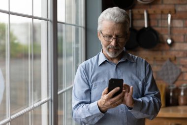 Telefonu kullanarak gözlük takan olgun bir adamı kapat.