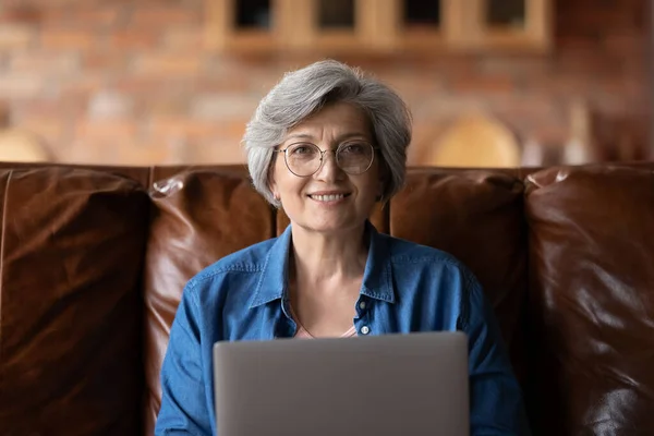 Портрет с улыбкой на голове взрослой женщины в очках с ноутбуком — стоковое фото