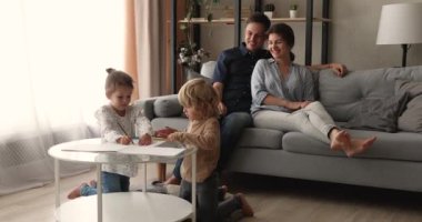 Mutlu ebeveynler kanepede dinleniyor çocuklar eskiz defterine çizim yapıyor.