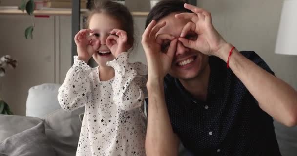 Padre hija mira a la cámara mostrando la forma de las gafas con los dedos — Vídeo de stock