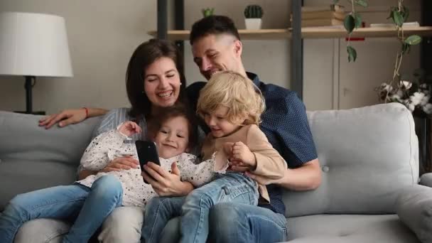 Çocuklu mutlu bir aile akıllı telefonları online eğlence aracı olarak kullanıyor. — Stok video