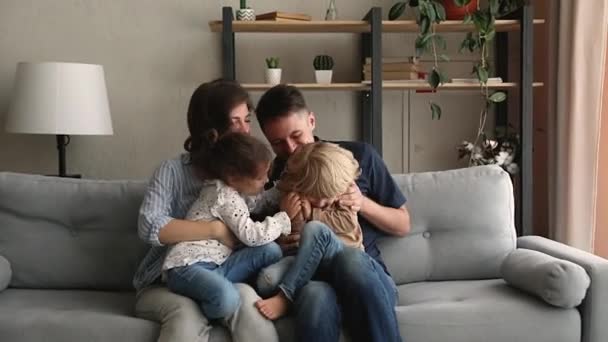 Ebeveynler ve çocuklar koltukta oturmuş birbirlerini gıdıklıyorlar. — Stok video
