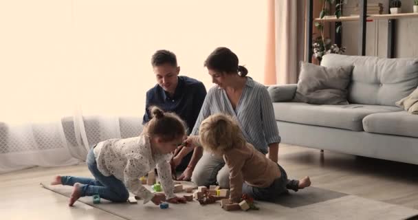 Föräldrar leker med små barn leksaker i vardagsrummet — Stockvideo