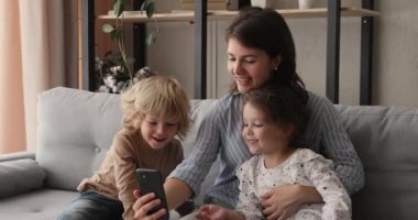 Anne ve çocuklar oyun oynuyor. Akıllı telefon kullanıyorlar.