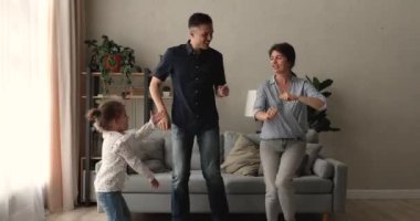 Modern evde kızı olan genç bir aile dans ediyor.