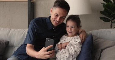 Baba ve kızı akıllı telefon kullanarak boş zamanın tadını çıkarıyorlar.