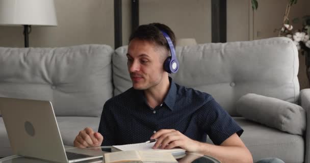 Guy usar auriculares hablar con el profesor usando videocall y portátil — Vídeo de stock