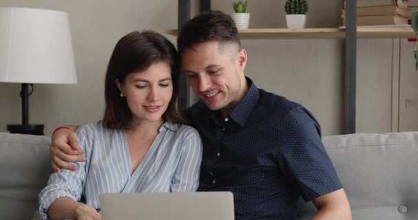 Пара сидеть на диване использовать ноутбук обсудить покупку в Интернете — стоковое видео