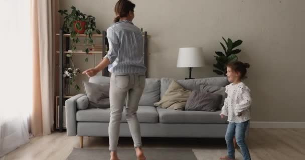 Actieve moeder en kleine dochter dansen in de woonkamer — Stockvideo