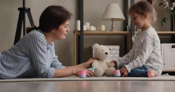Mamá y su hija jugando a dar té a peluche osito de peluche — Vídeos de Stock