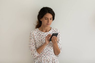 Beyaz kadın, gri arka planda cep telefonu kullanarak izole edilmiş.