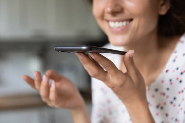 Gülümseyen kadın akıllı telefondan sesli mesaj kaydediyor.