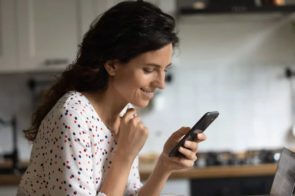 Lächelnde Frau nutzt modernes Smartphone zu Hause — Stockfoto