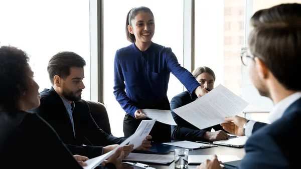 Glimlachende vrouwelijke werknemer delen papierwerk op vergadering — Stockfoto
