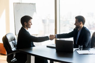 Gülümseyen işadamları ofiste el sıkışıyorlar.