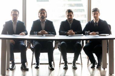 Ciddi iş adamlarının portresi ofiste oturuyor.