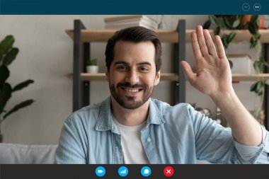 Gülümseyen genç yakışıklı adam web kamerasına bakıyor, arkadaşlarını selamlıyor..