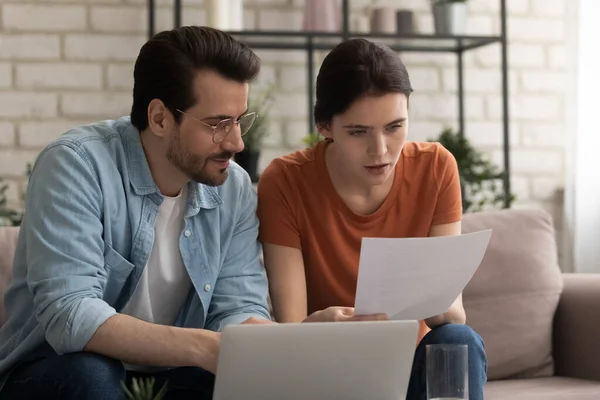 Geconcentreerde echtgenoten met een duizendjarig gezin die binnenlandse betalingen overwegen. — Stockfoto