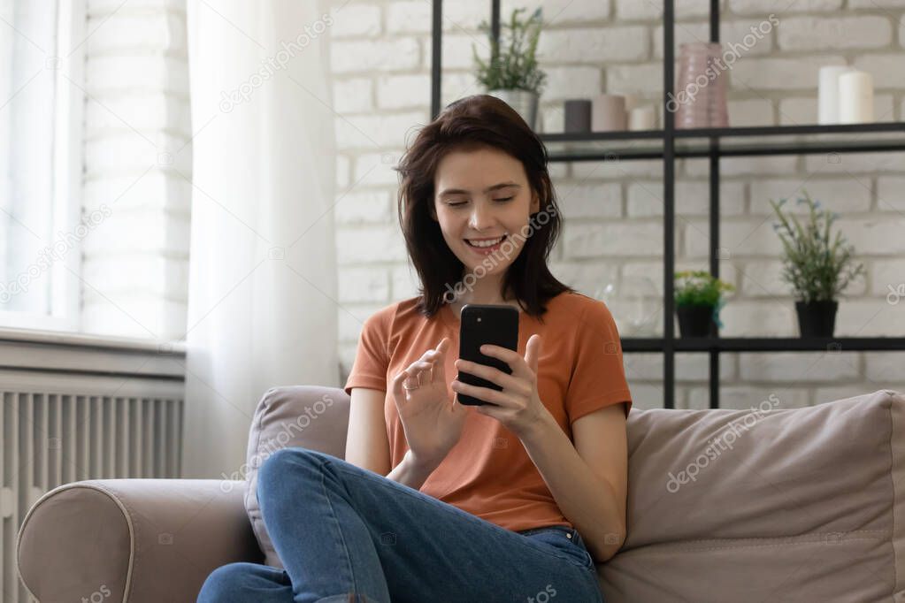 Relaxed millennial smiling woman using mobile phone applications.