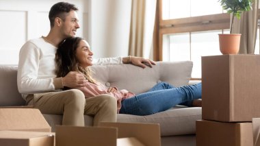 Couple resting on couch on moving day to new home clipart