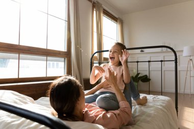 Sıcak, güneşli yatak odasında mutlu anne ve neşeli kızı oynuyor.