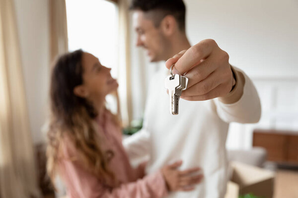 Young couple showing keys to the new house close up