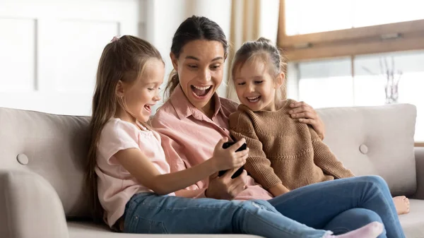 Matka a děti sedět na gauči baví pomocí smartphonu — Stock fotografie