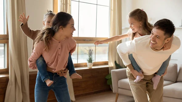 Rodiče piggyback jízda na malých dcerách těšit playtime o víkendu — Stock fotografie