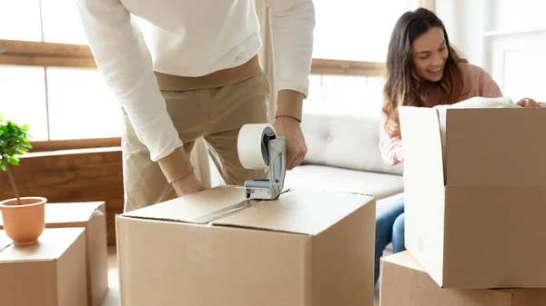 Couple sealing cardboard boxes preparing relocating to new apartment