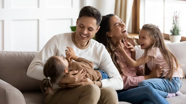 Ouders spelen met dochters zitten op de bank in de woonkamer — Stockfoto