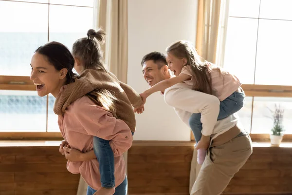 Allegro coppia cavalcando piccole figlie giocare insieme a casa — Foto Stock