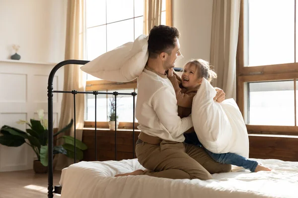 Papà e figlioletta si siedono a letto a combattere con i cuscini — Foto Stock