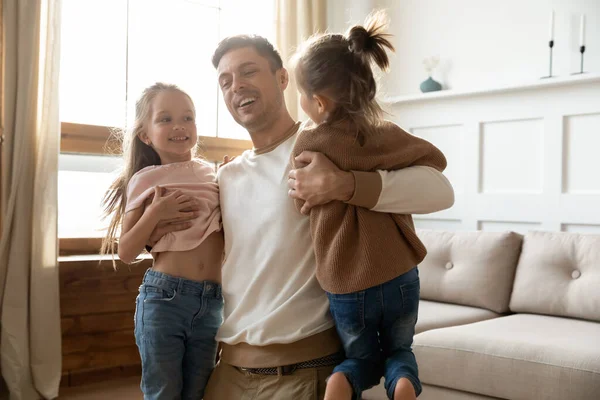 Forte papà che porta sollevando tenendo in mano due figlie — Foto Stock