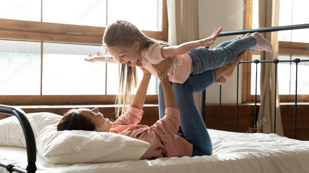 In the morning woman lies in bed play with daughter