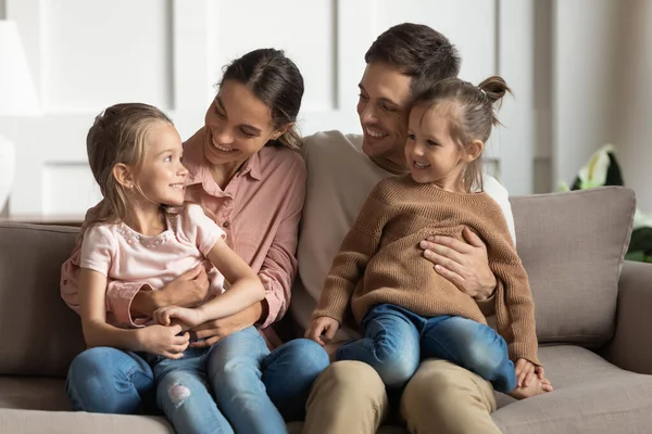 Kleine dochters zitten op ouders ronden praten rusten op de bank — Stockfoto