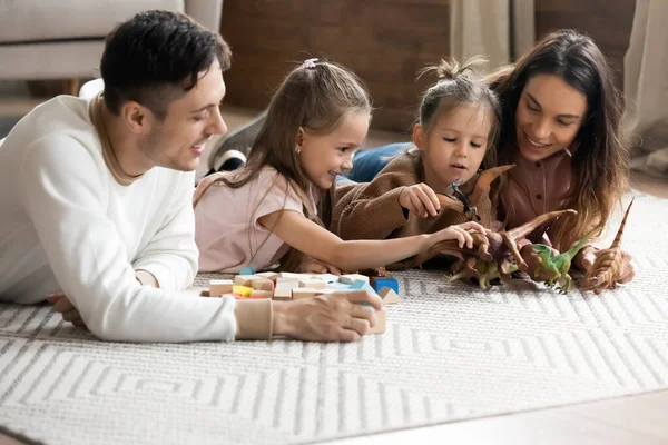 Coppia sdraiata sul pavimento giocare con le figlie piccole — Foto Stock