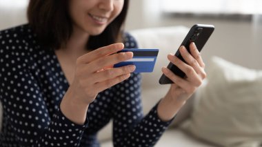 Kapatın gülümseyen Asyalı kadın plastik kart ve telefon tutuyor.