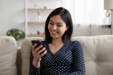 Gülen Asyalı genç kadın bir ekrana yakından bakıyor.