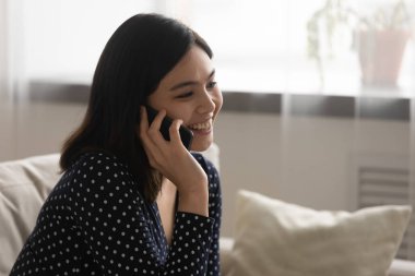 Kapatın gülümseyen Asyalı genç bayan telefonda konuşuyor.